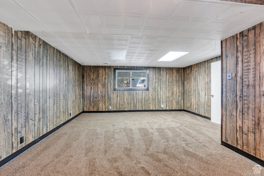 Basement featuring wooden walls, baseboards, and carpet flooring