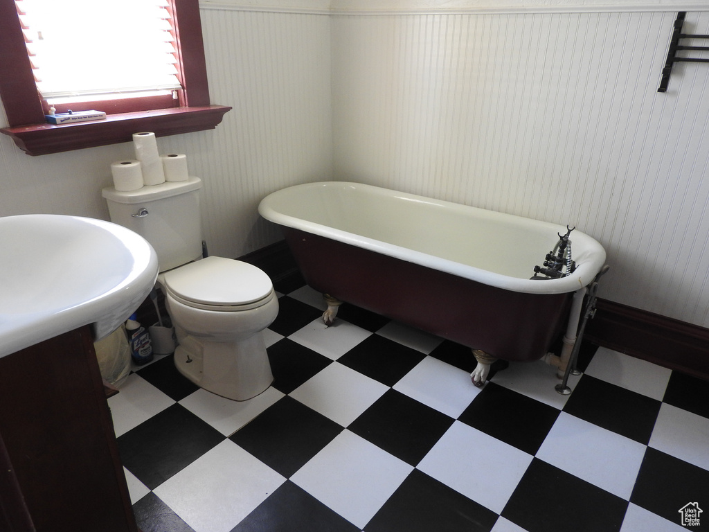 Bathroom featuring tile patterned floors, a soaking tub, and toilet
