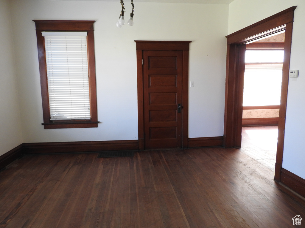 Empty room with baseboards and dark wood-style flooring