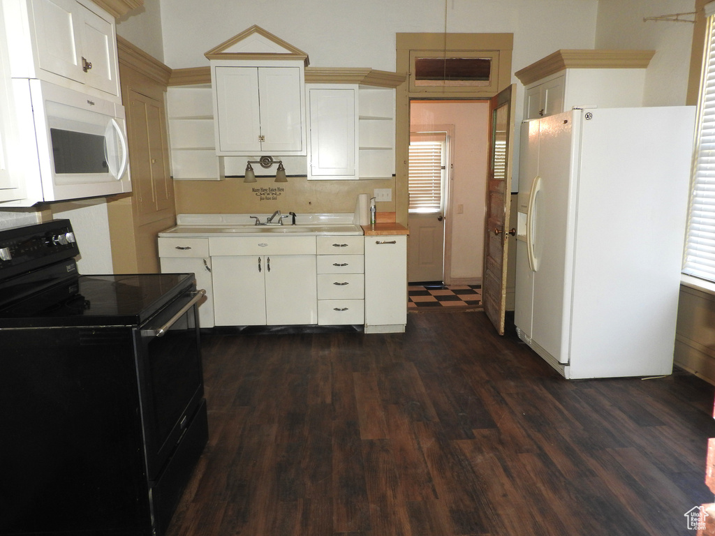 Kitchen with dark wood-style flooring, open shelves, a sink, light countertops, and white appliances