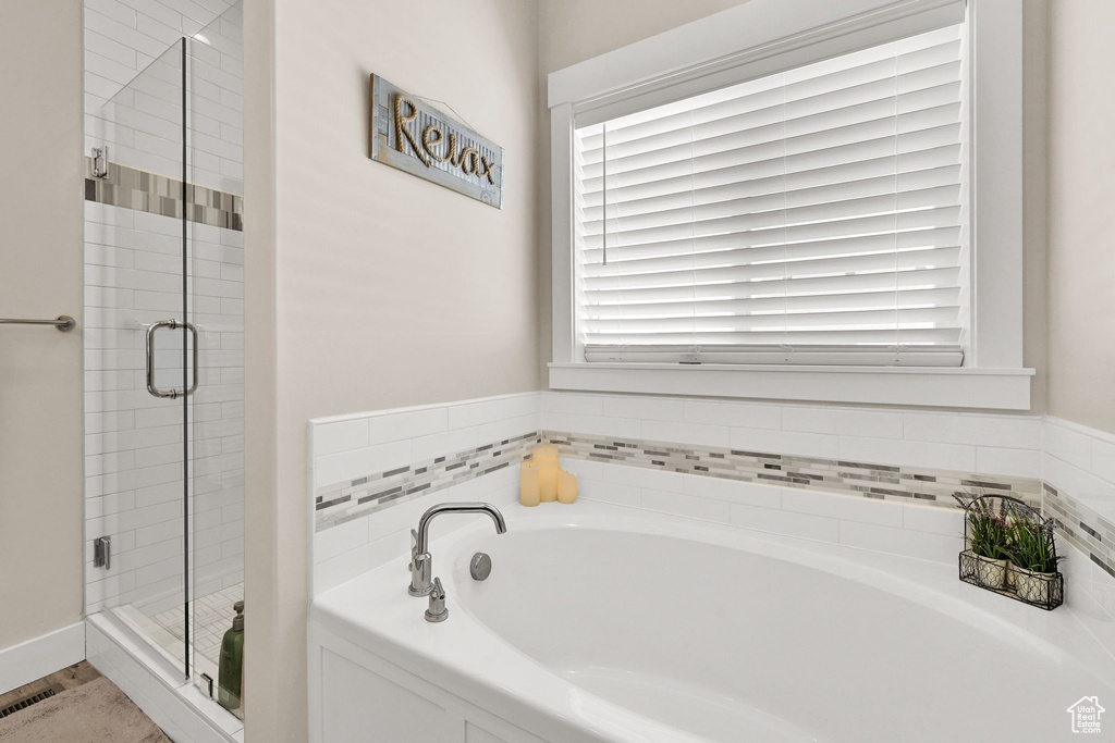 Bathroom with a garden tub, a healthy amount of sunlight, and a shower stall