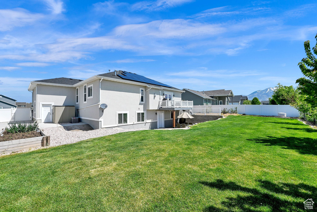 Rear view of property with a yard, a deck, a fenced backyard, and stucco siding