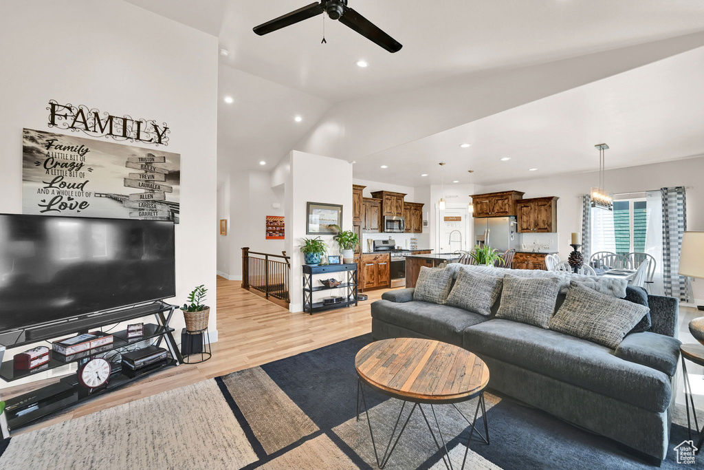 Living room featuring a ceiling fan, vaulted ceiling, light wood-style flooring, and recessed lighting