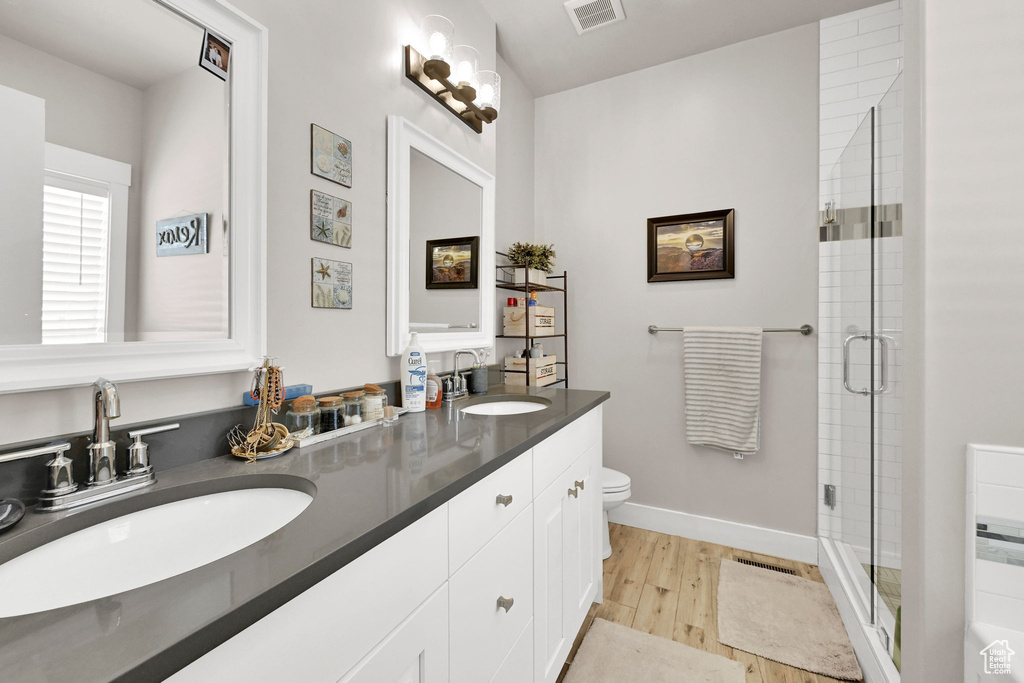 Bathroom with a sink, toilet, wood finished floors, and visible vents