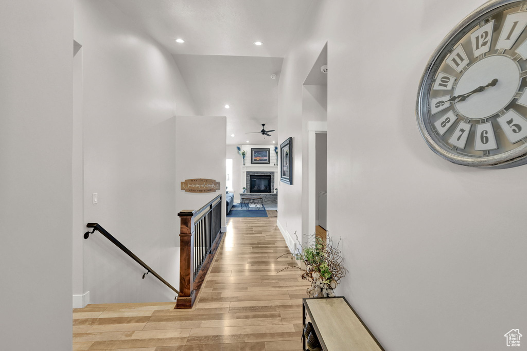 Hall with a towering ceiling, baseboards, light wood finished floors, an upstairs landing, and recessed lighting