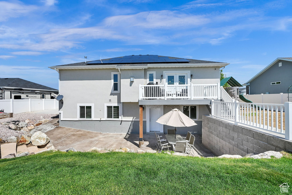 Rear view of property featuring a patio, french doors, roof mounted solar panels, and stucco siding