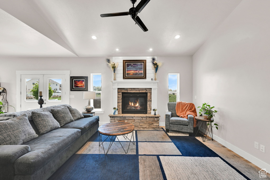 Living room with recessed lighting, ceiling fan, a stone fireplace, and wood finished floors