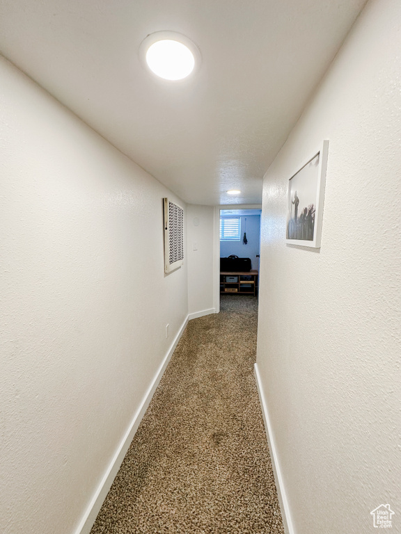Hall with baseboards, carpet, and visible vents