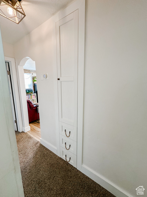 Hallway featuring carpet floors, arched walkways, and baseboards