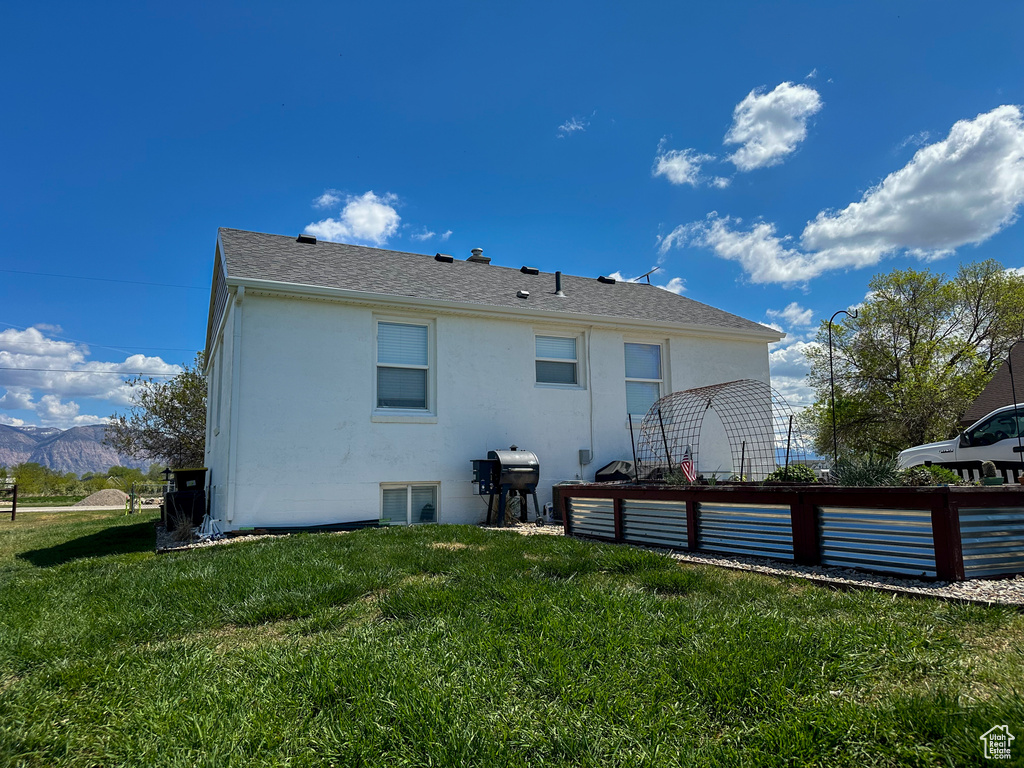 Rear view of house with a mountain view, stucco siding, and a yard
