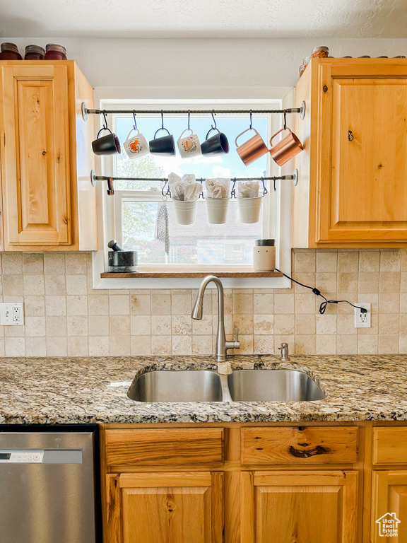 Kitchen with a sink, decorative backsplash, stainless steel dishwasher, and light stone countertops