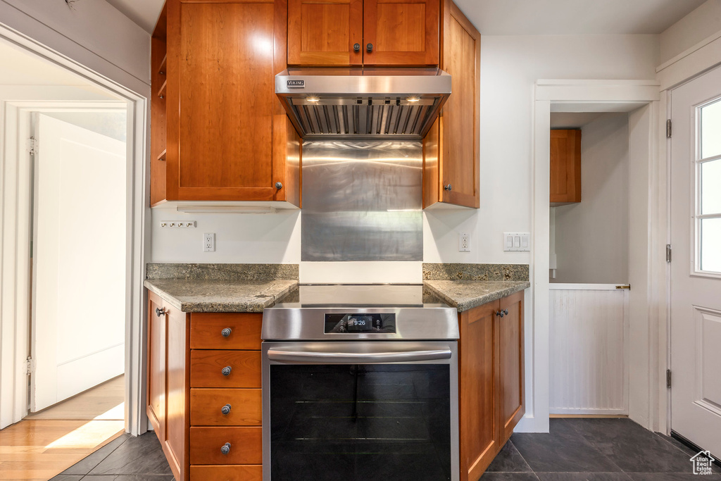 Kitchen with dark countertops, stainless steel oven, brown cabinets, and extractor fan