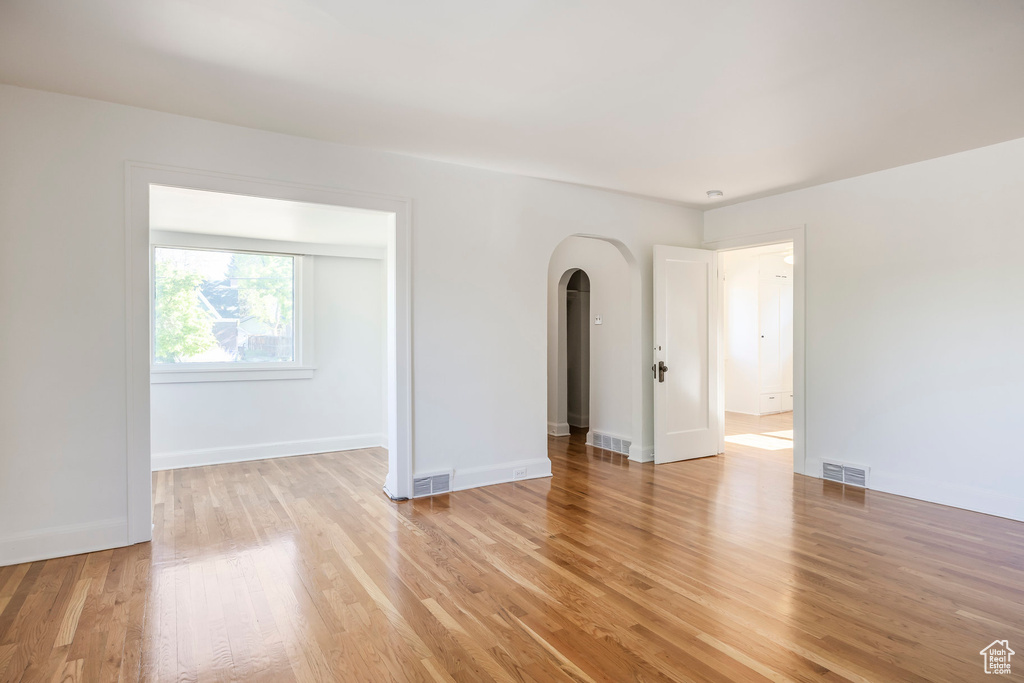 Spare room featuring arched walkways, visible vents, and light wood-style flooring