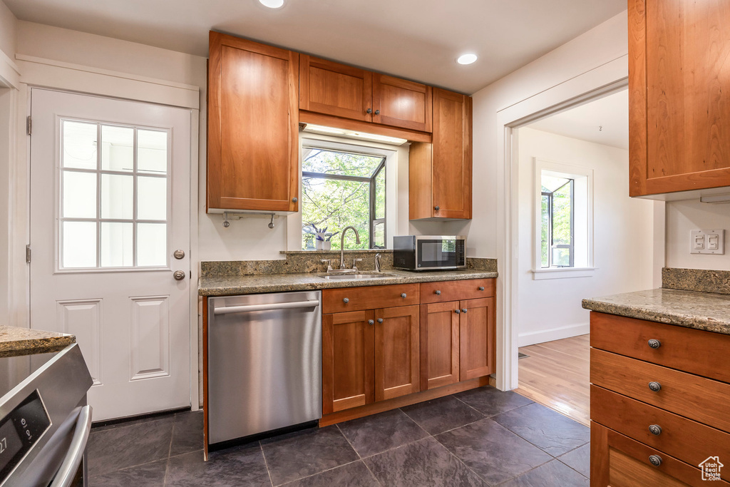 Kitchen with brown cabinets, a sink, dishwasher, recessed lighting, and baseboards
