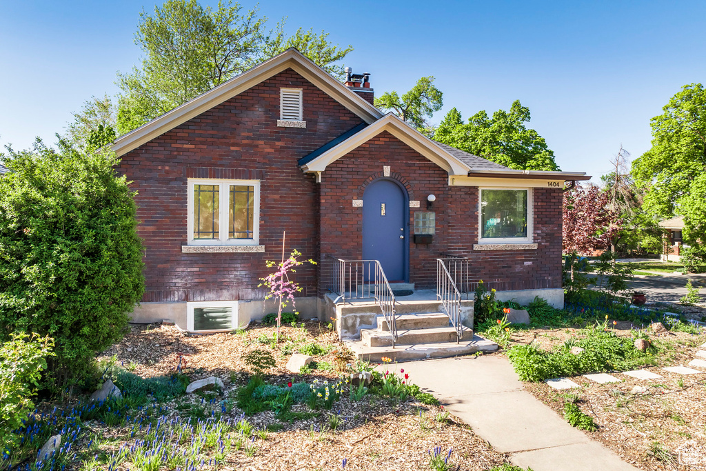 Bungalow-style home featuring brick siding and a chimney