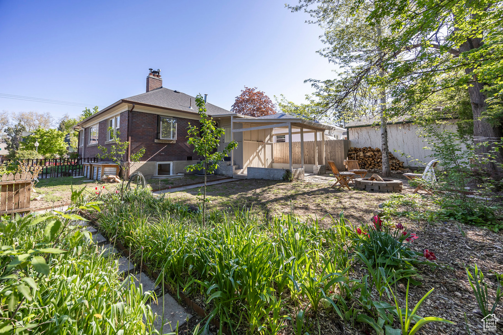 Back of property with brick siding, fence, a chimney, and an outdoor fire pit