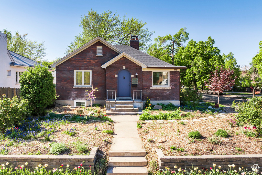 Bungalow with brick siding, fence, and a chimney