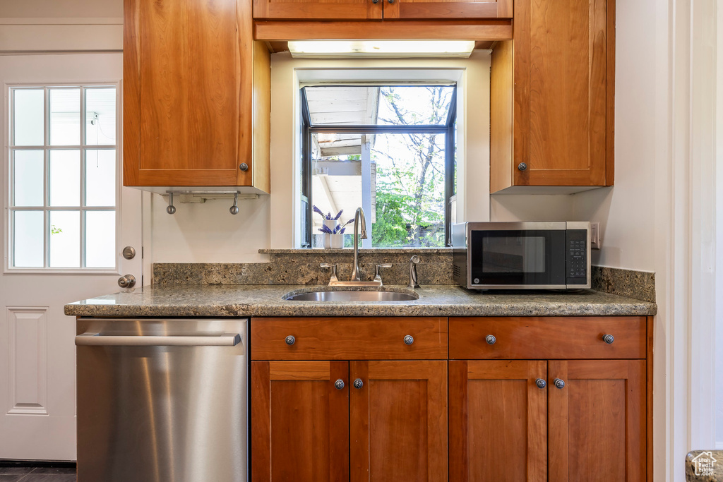 Kitchen with appliances with stainless steel finishes, brown cabinetry, and a sink