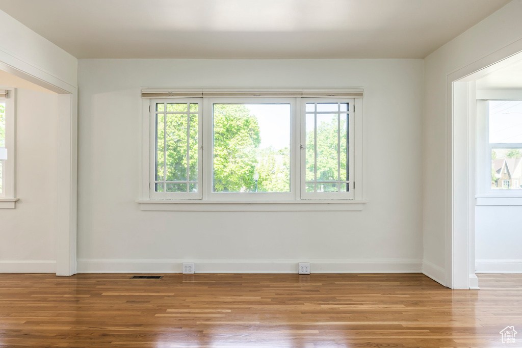Unfurnished room with baseboards, plenty of natural light, wood finished floors, and visible vents