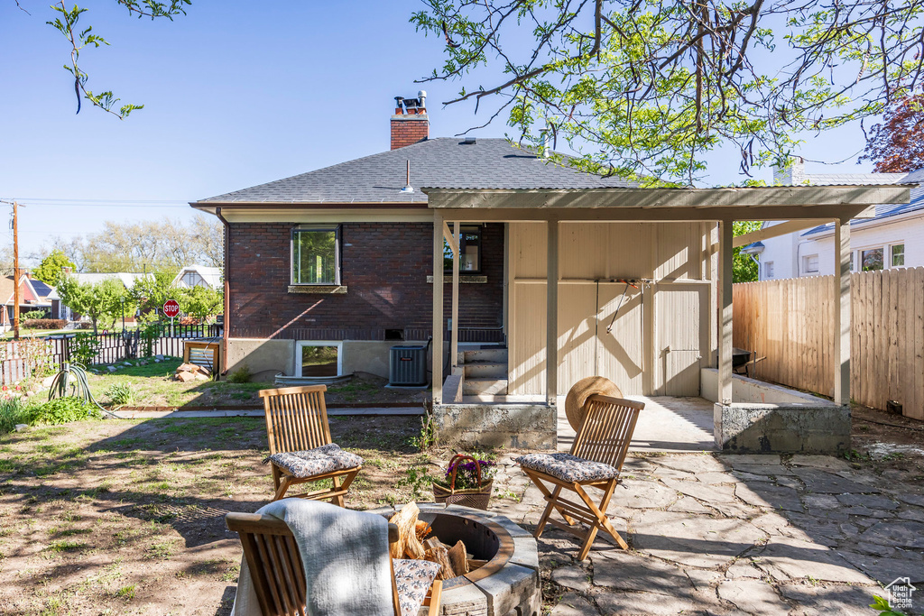 Back of property featuring fence, a chimney, a fire pit, and roof with shingles