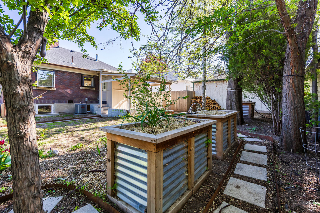 View of yard featuring central AC, a garden, fence, and entry steps