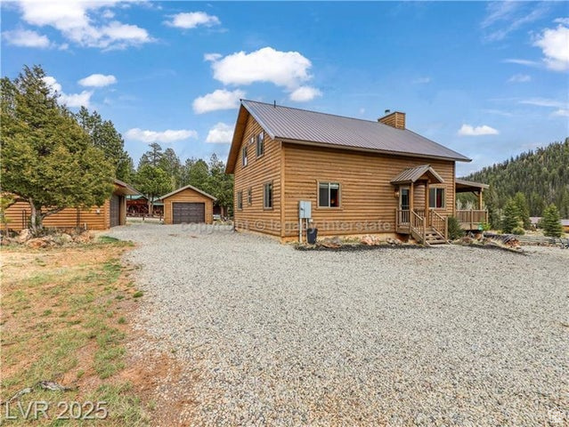 View of front of house with an outdoor structure, a garage, covered porch, a chimney, and metal roof