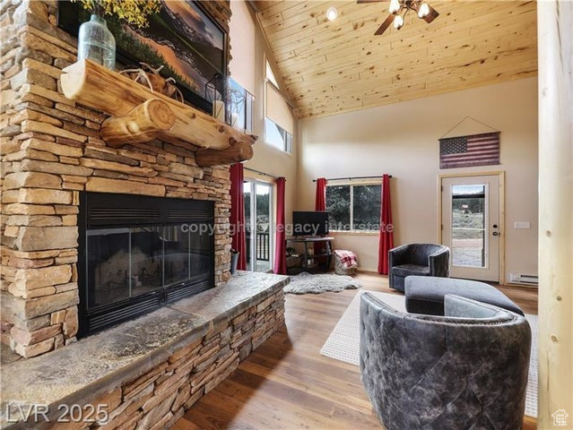 Living area featuring baseboard heating, a fireplace, high vaulted ceiling, wooden ceiling, and wood finished floors