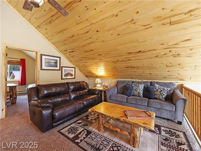 Carpeted living area featuring vaulted ceiling and wooden ceiling
