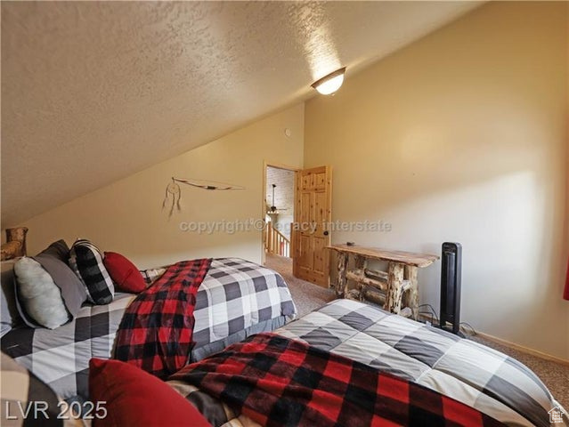 Bedroom featuring carpet floors, a textured ceiling, and vaulted ceiling