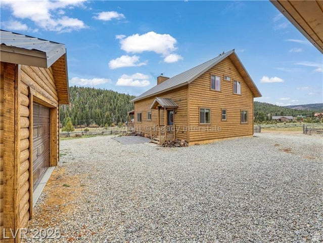 View of home\'s exterior with driveway, a chimney, and metal roof