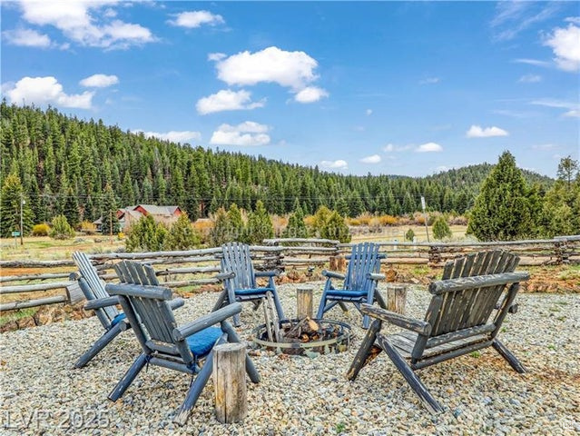View of yard featuring fence, a fire pit, and a wooded view