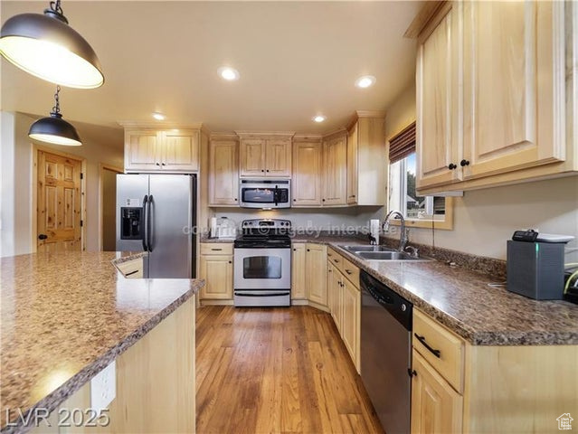 Kitchen featuring light brown cabinetry, recessed lighting, light wood-type flooring, a sink, and stainless steel appliances