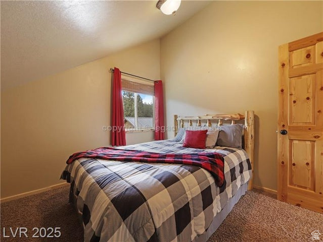 Bedroom with carpet flooring, baseboards, and lofted ceiling