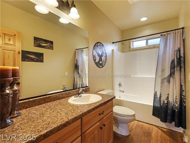Full bath featuring vanity, wood finished floors, toilet, and shower / bath combo with shower curtain