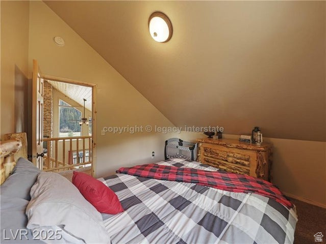 Bedroom featuring carpet floors and vaulted ceiling