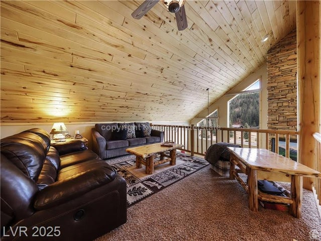 Carpeted living room with a ceiling fan, vaulted ceiling, and wooden ceiling
