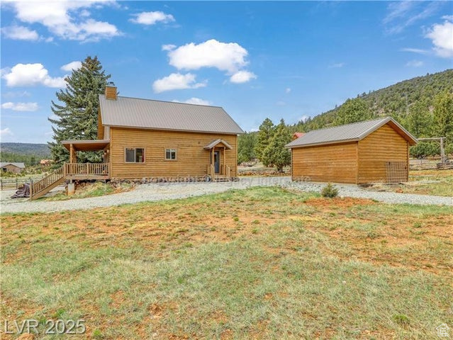 View of side of property featuring a lawn, a mountain view, a chimney, and metal roof