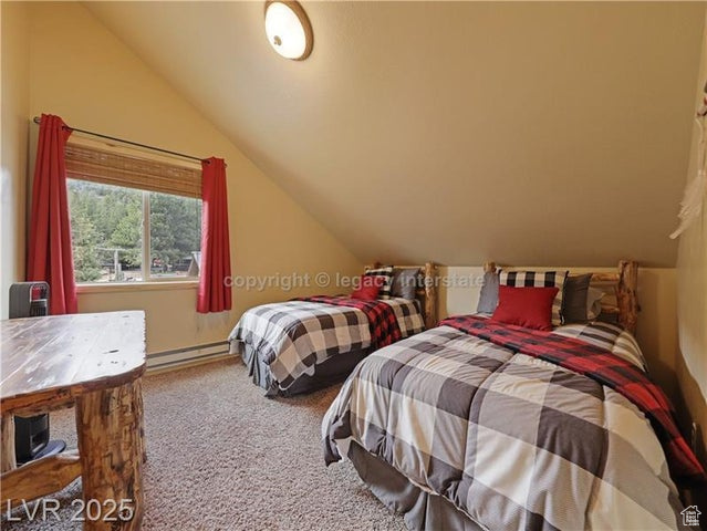 Carpeted bedroom with a baseboard heating unit and lofted ceiling