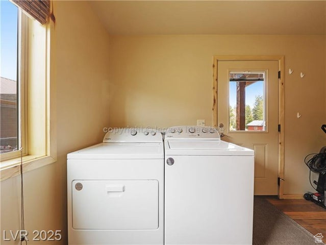 Clothes washing area featuring laundry area, wood finished floors, and washer and dryer