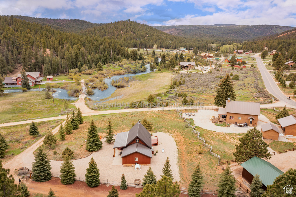 Aerial view of property and surrounding area with a forest and a mountainous background