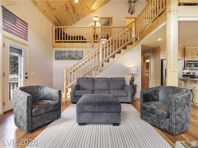 Living area featuring high vaulted ceiling, wood ceiling, stairs, and wood finished floors
