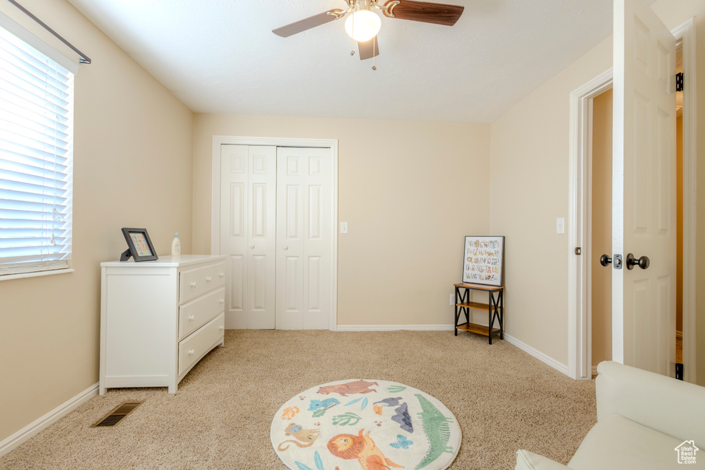 Interior space featuring visible vents, a closet, light carpet, baseboards, and ceiling fan