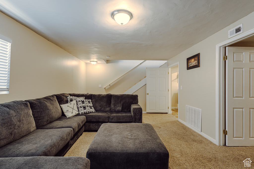Living room with stairway, baseboards, light carpet, and visible vents