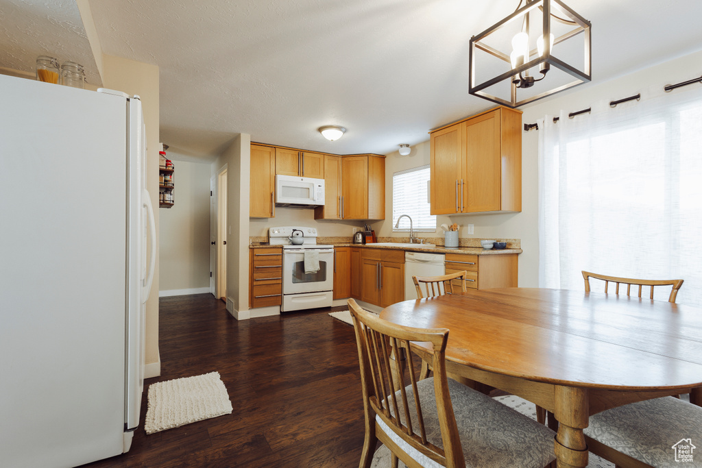 Dining space featuring dark wood-type flooring, baseboards, and a notable chandelier
