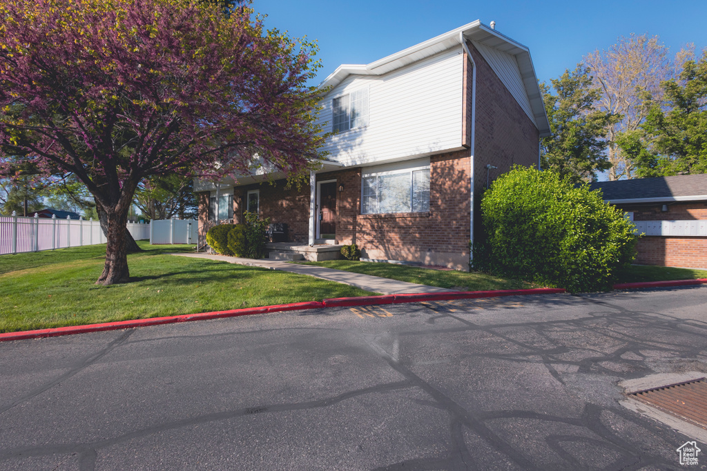 View of front of property featuring brick siding, a front lawn, and fence