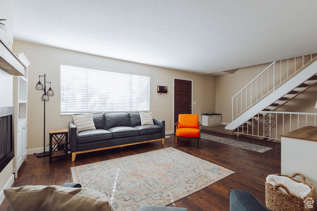 Living room featuring baseboards, stairs, wood finished floors, and a fireplace