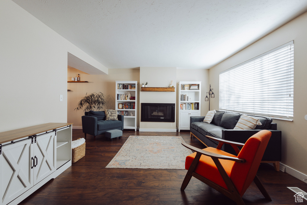 Living area with baseboards, a fireplace, dark wood-style flooring, and visible vents