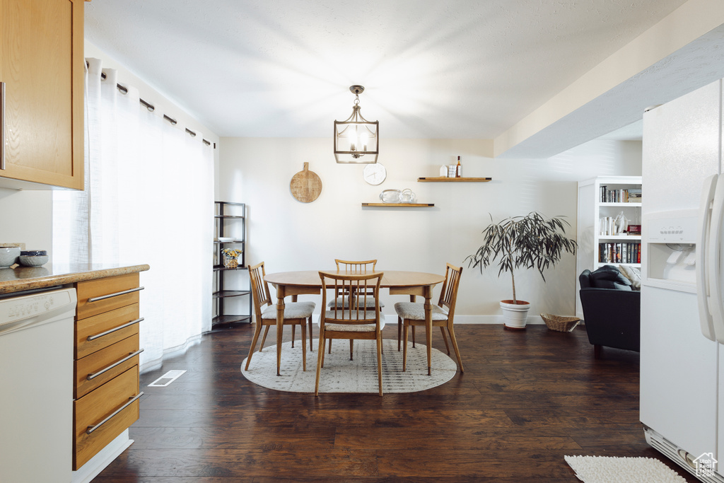 Dining area featuring dark wood-style flooring and visible vents