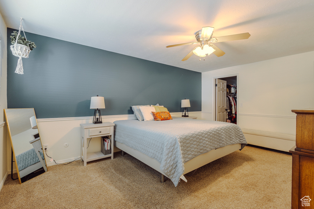 Carpeted bedroom featuring ceiling fan, a spacious closet, and a closet