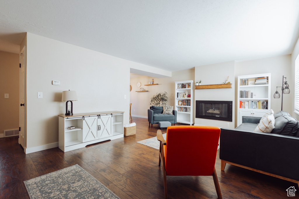 Living room featuring baseboards, visible vents, a large fireplace, and wood finished floors